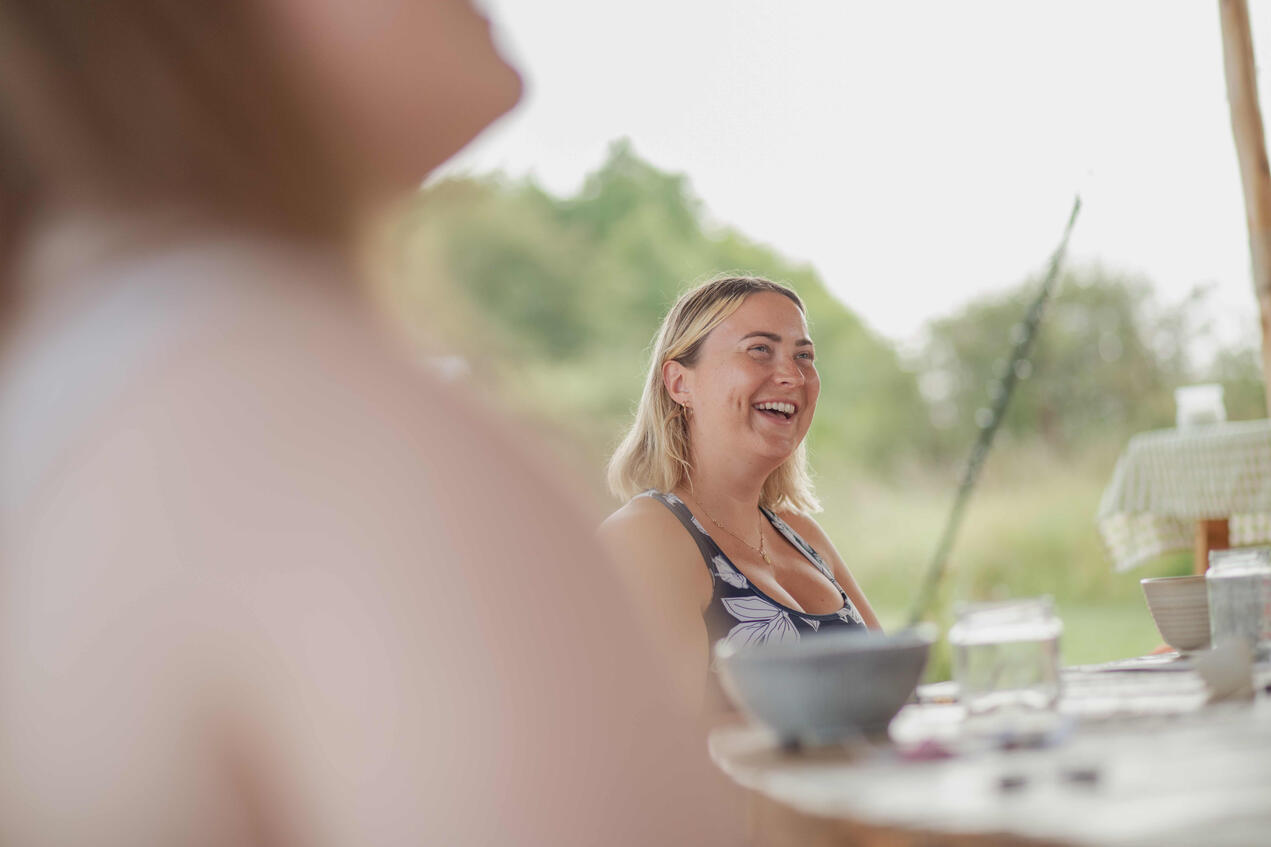 Cinematic brand photography of a retreat facilitator with eyes closed, hand on heart, guiding a moment of reflection under a tent.