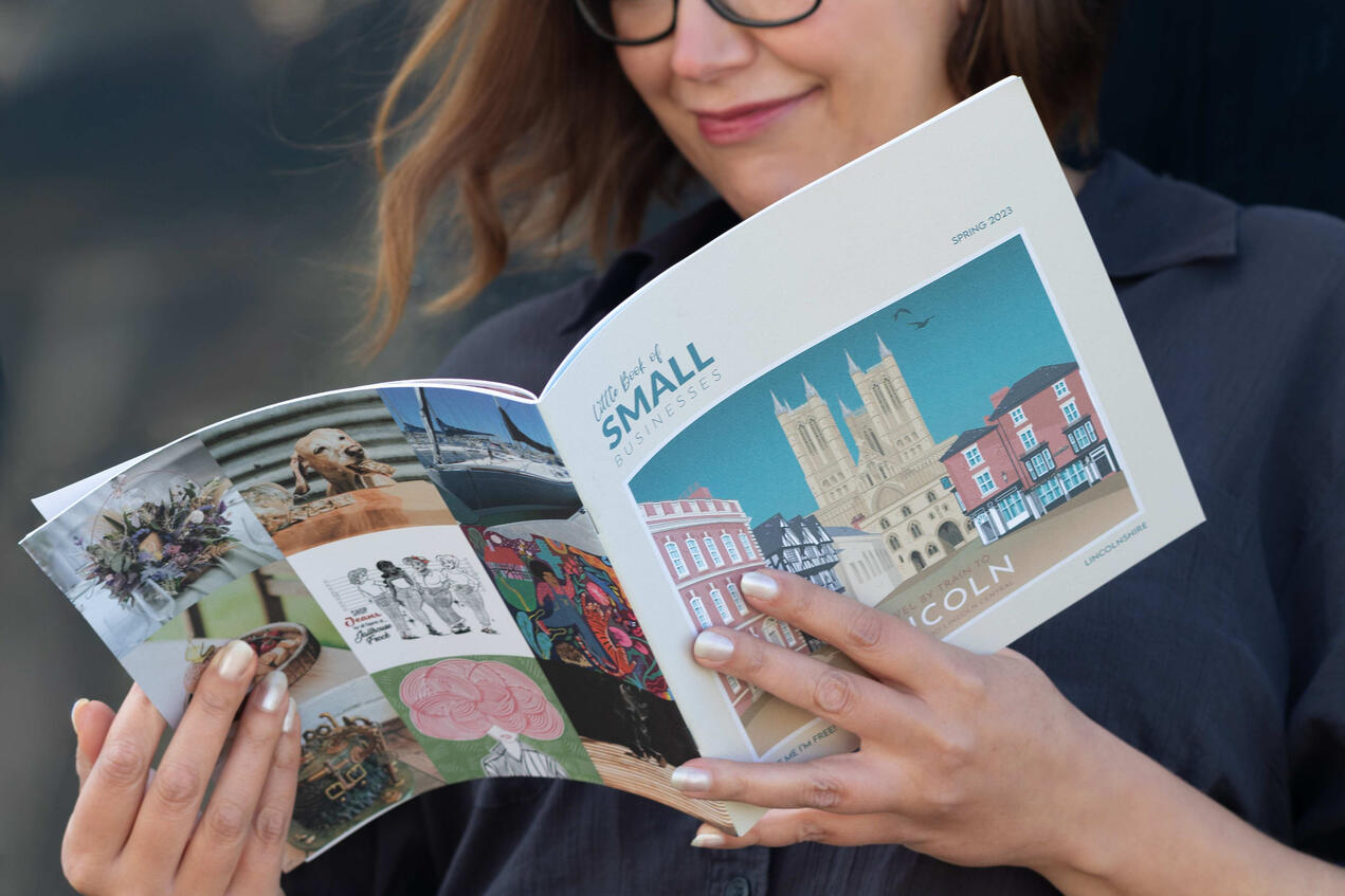 Close-up brand photo of a Lincoln publisher smiling while holding her business magazine, focus on the publication itself.