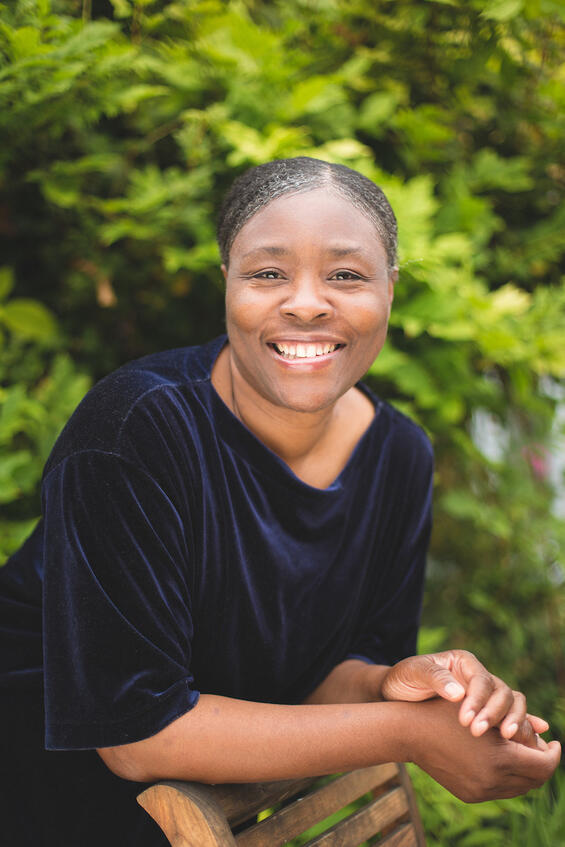 Straightforward confidence portrait of a business coach, leaning and smiling directly at the camera.