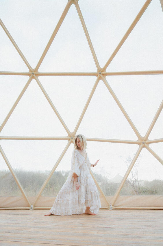 Wide shot of a movement facilitator in a dome space, mid-pose, during a wellness photography session